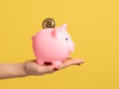 Close up side view portrait of woman hand holding piggy bank with golden coin.