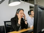 Stock photo of a call center employee who appears to be experiencing burnout.