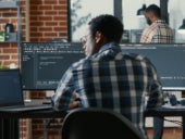 IT professional working on coding with a computer on an office desk.