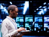 An IT professional working on his laptop on a data center facility.